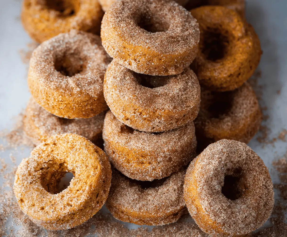 Freshly baked pumpkin spice donuts topped with cinnamon sugar on a rustic plate, perfect for fall treats