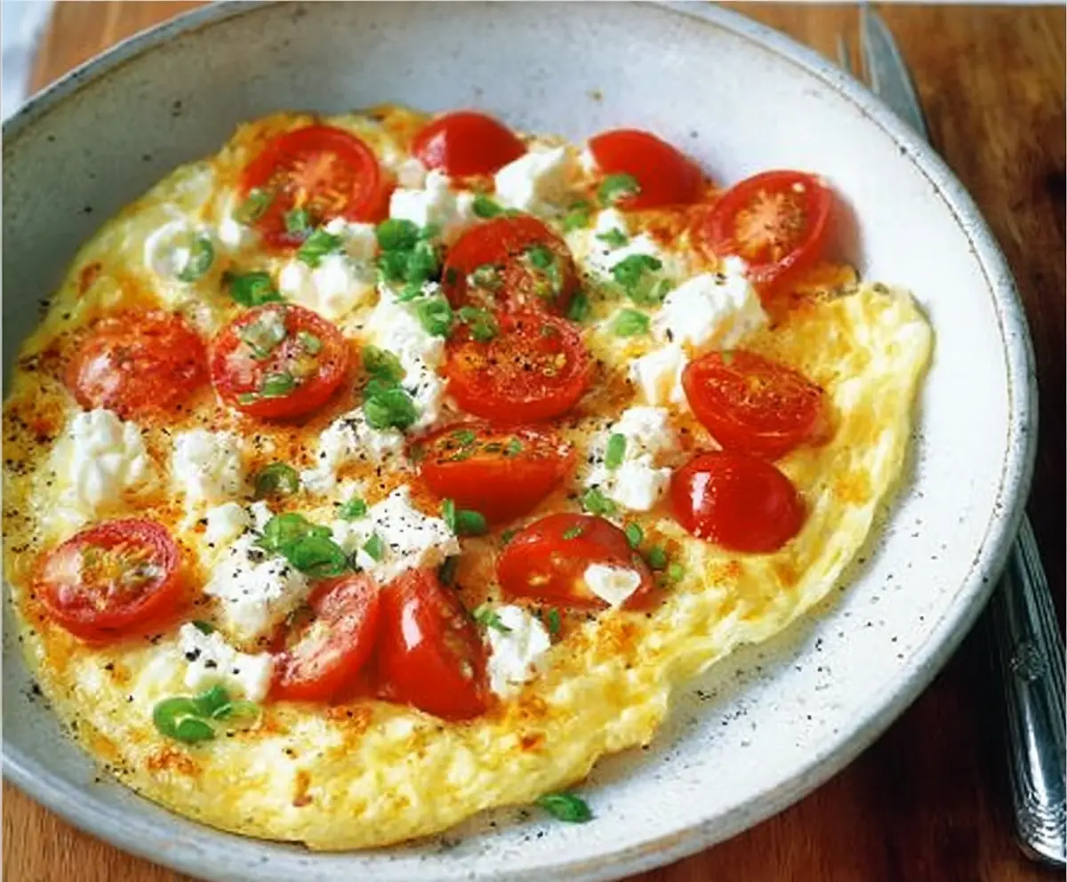 Delicious feta and tomato omelet served on a plate, perfect for breakfast or brunch.