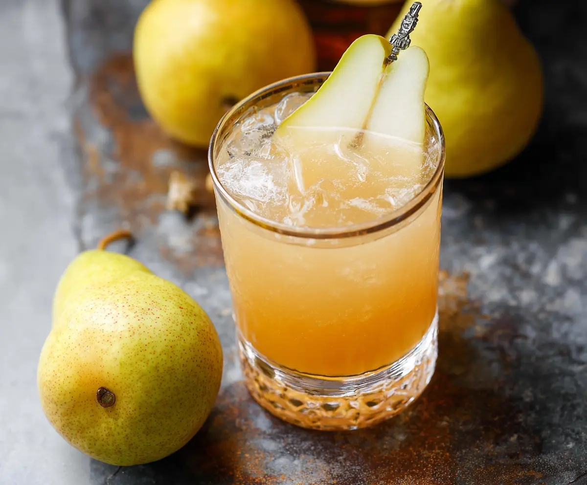 Refreshing Ginger Pear Bourbon Cocktail garnished with pear slices and fresh ginger in a elegant glass.