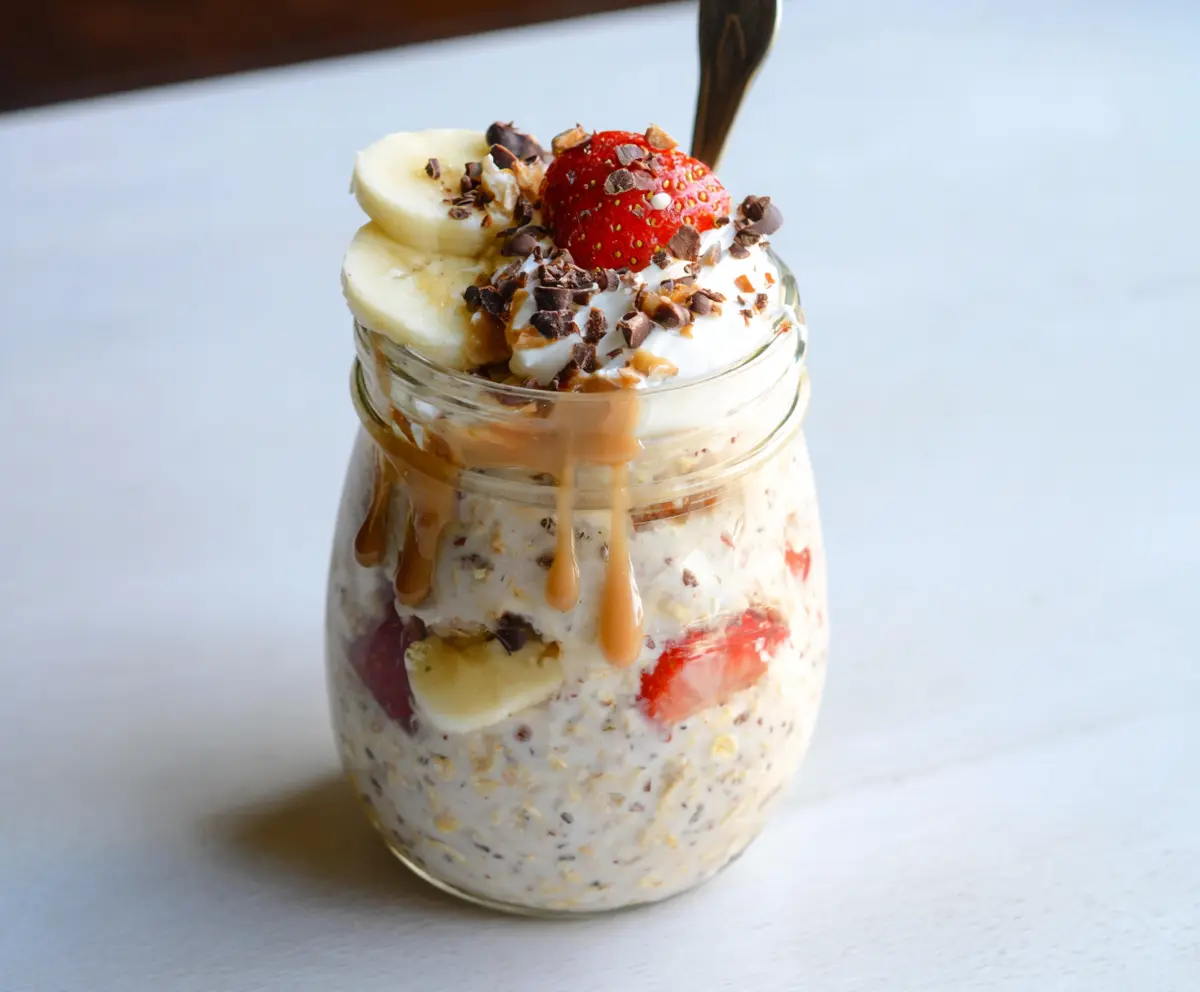 Creamy Banana Split Overnight Oats with fresh bananas, strawberries, and chocolate chips in a glass jar.
