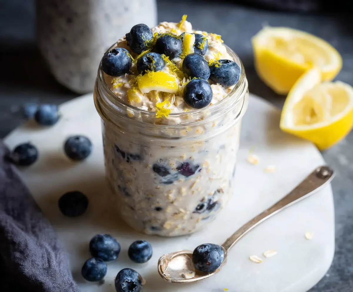 Creamy blueberry lemon overnight oats in a glass jar, topped with fresh blueberries and lemon zest.