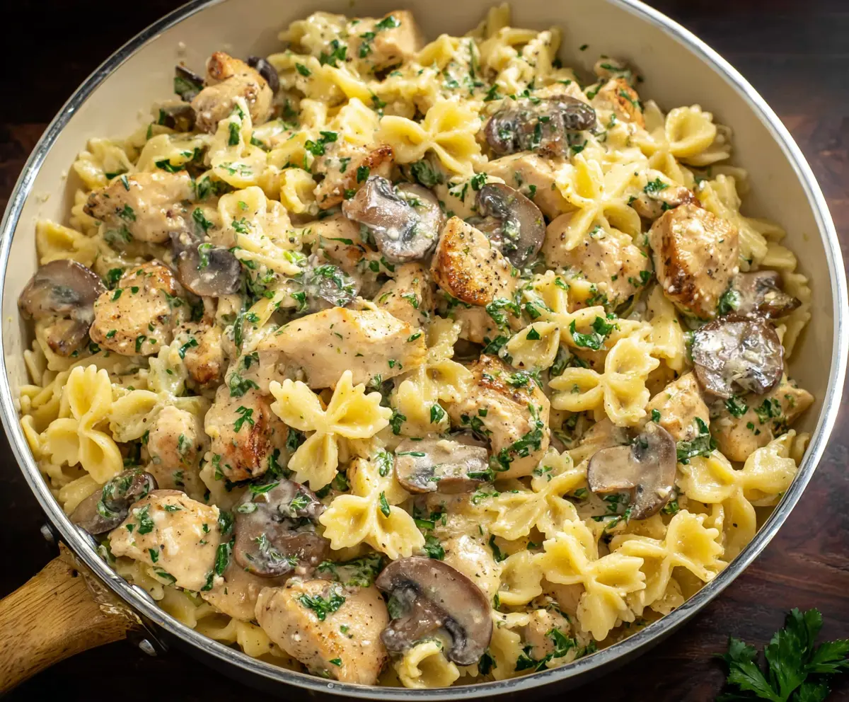Creamy chicken mushroom pasta dish served with fresh herbs and grated cheese.