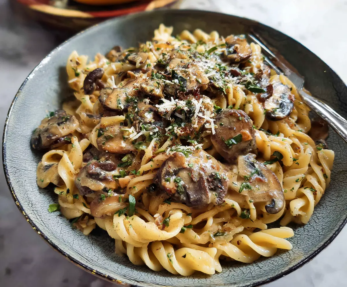 Delicious mushroom pasta with creamy sauce, beautifully plated on a white dish.