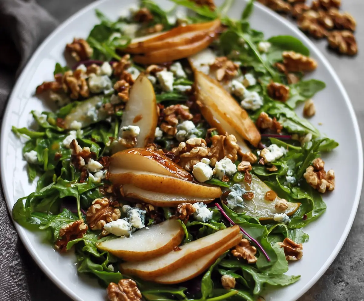 Fresh arugula and pear salad topped with crumbled blue cheese and walnuts, perfect for a healthy lunch.