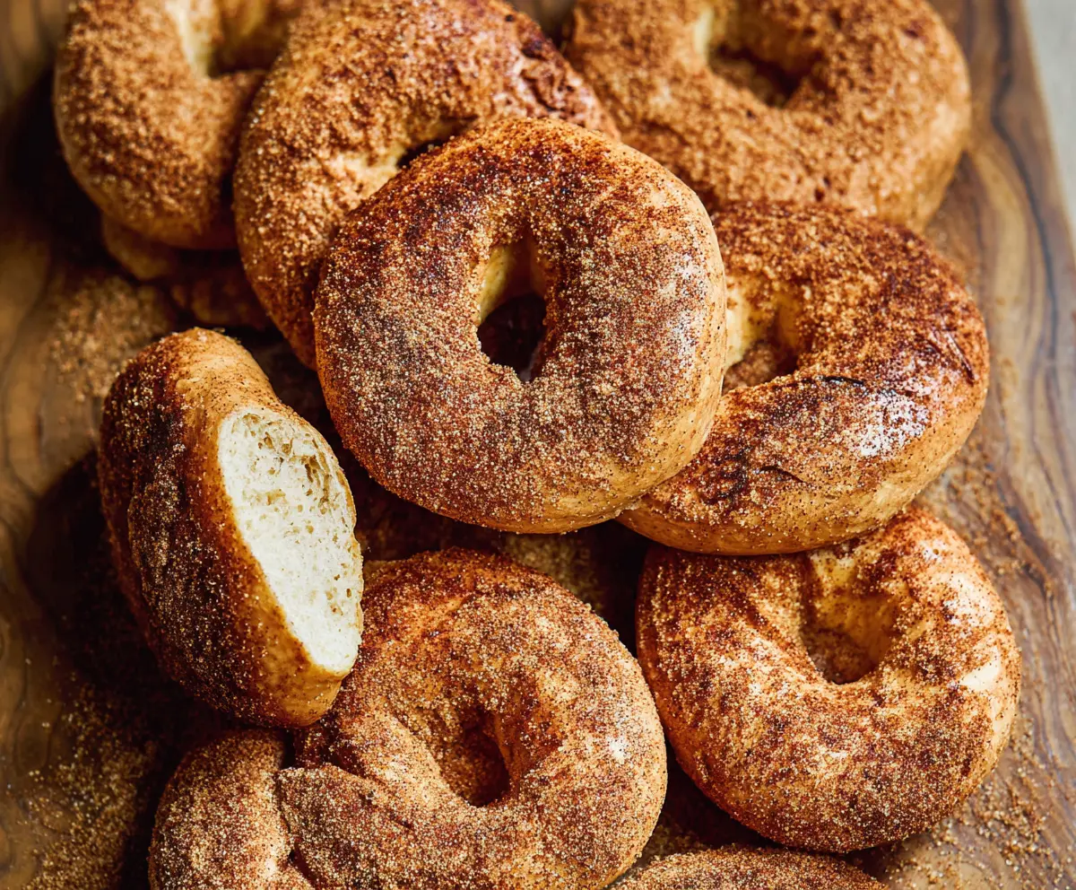 Freshly baked cinnamon bagels with a golden crust and cinnamon swirl topping on a rustic wooden board.