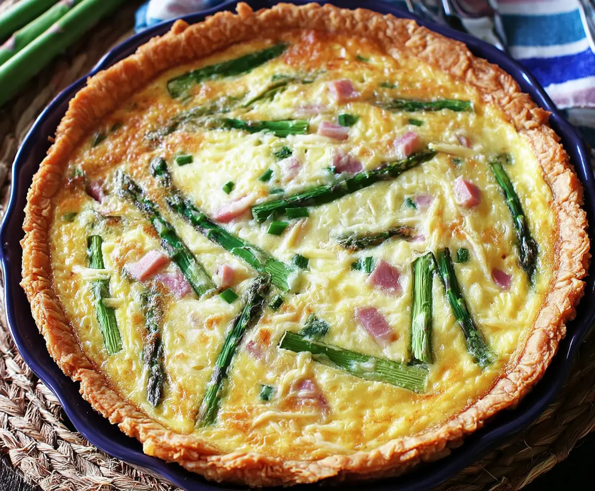 Delicious homemade ham and asparagus quiche with a golden crust and fresh ingredients on a rustic plate